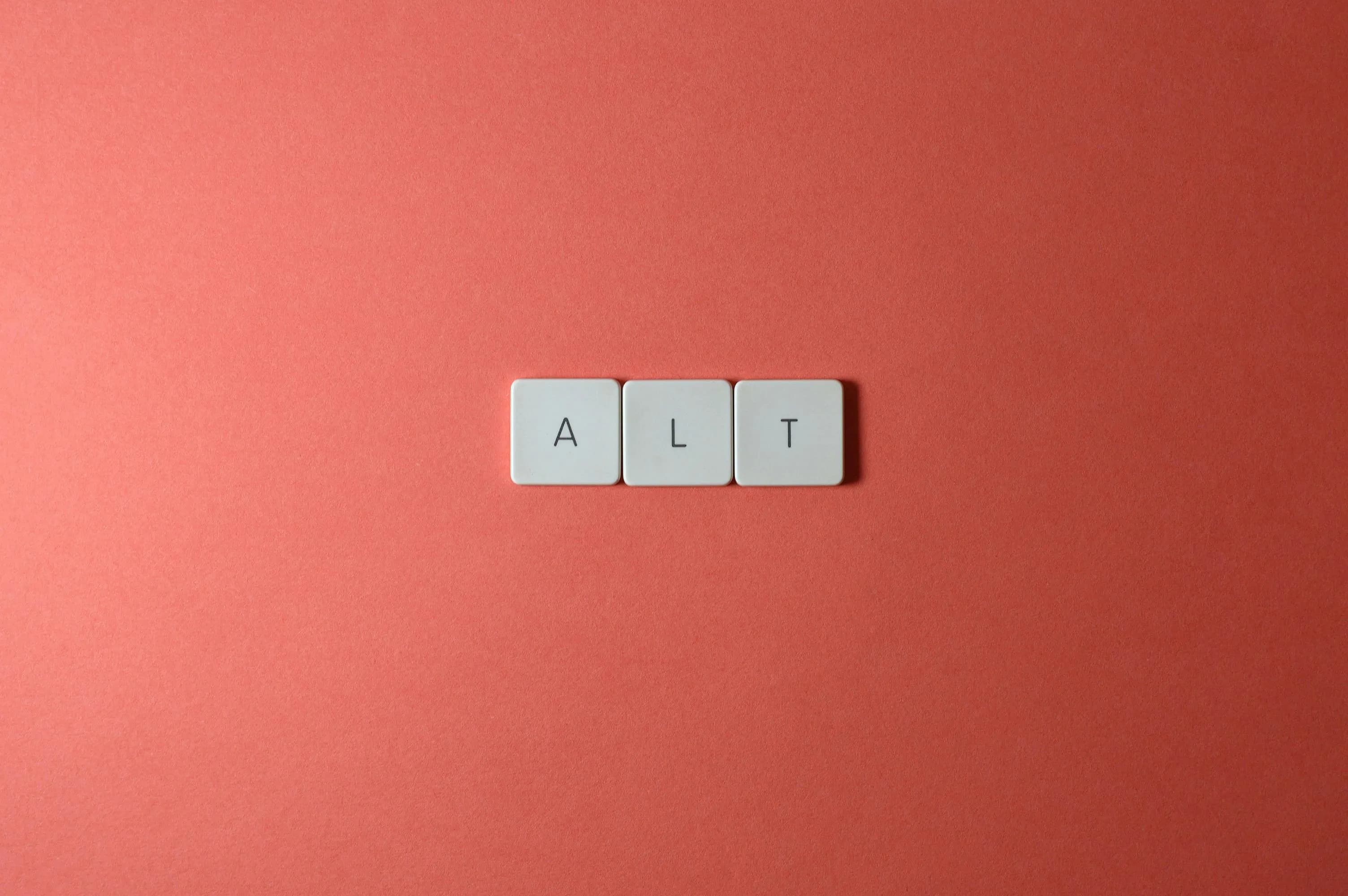 The letters A, L and T printed on three white keycaps against a red background